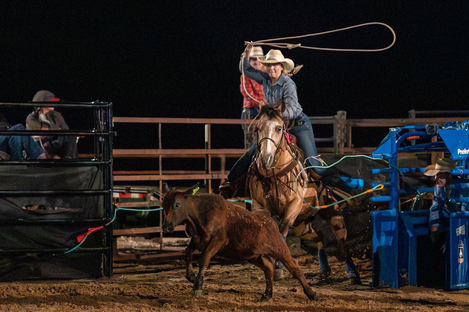 Breakaway roper swinging a loop while pursuing a calf in the WSE arena